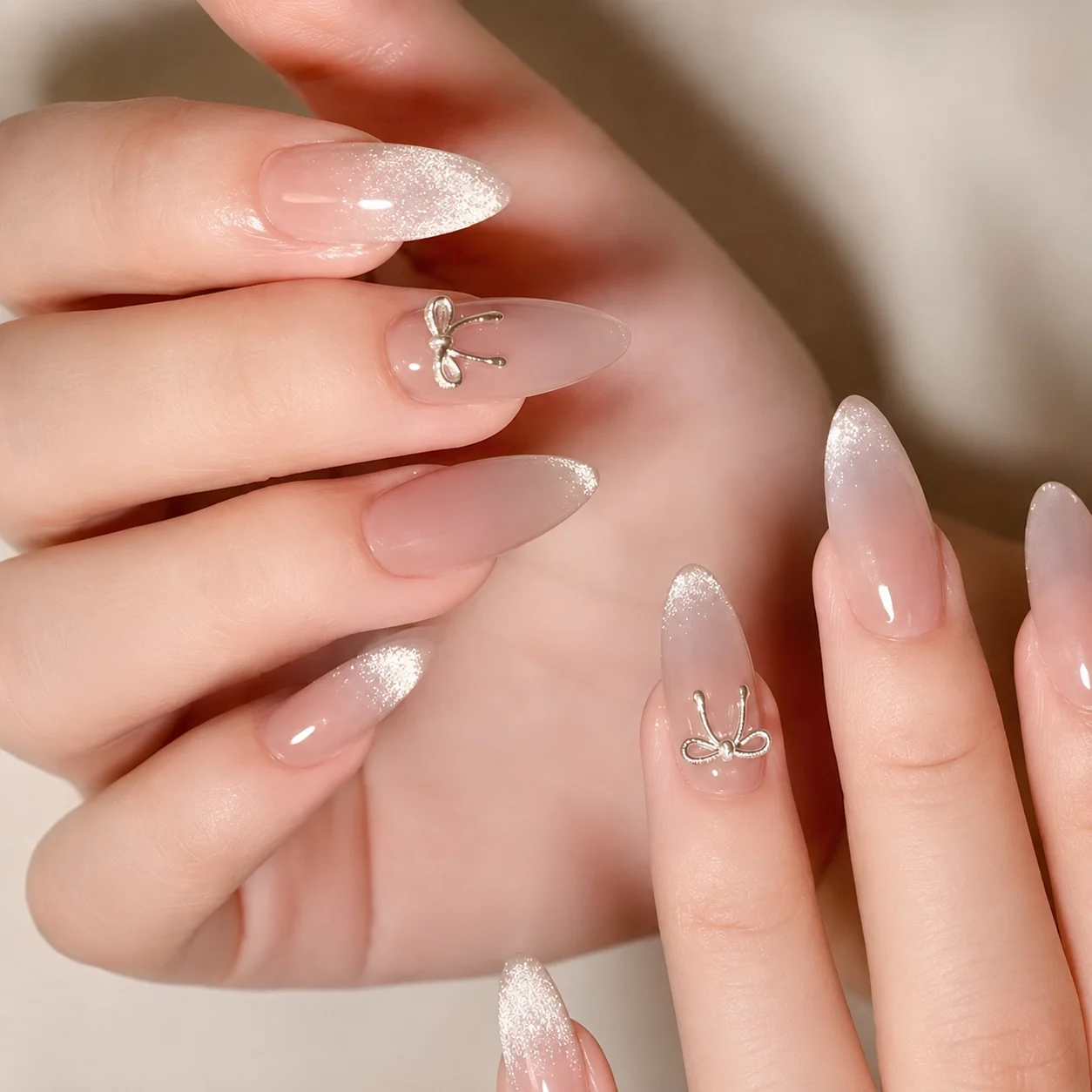 Nude nails with bow charms and glitter